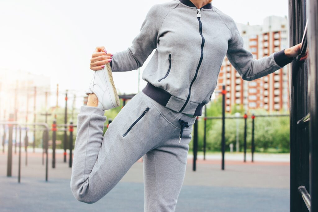 Attractive fit young woman in grey sport wear the doing warm up stretching before training on the street workout area. The healthy lifestyle in city